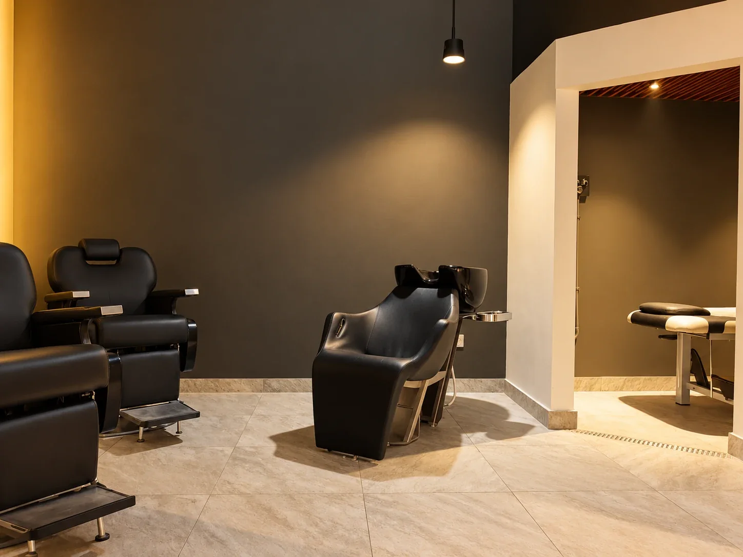 A reclining hair-wash chair under a pendant light, with the massage room beyond